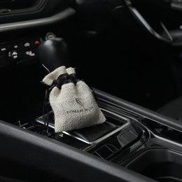 The Magic Charcoal jute pouch resting on the gear selector of a car